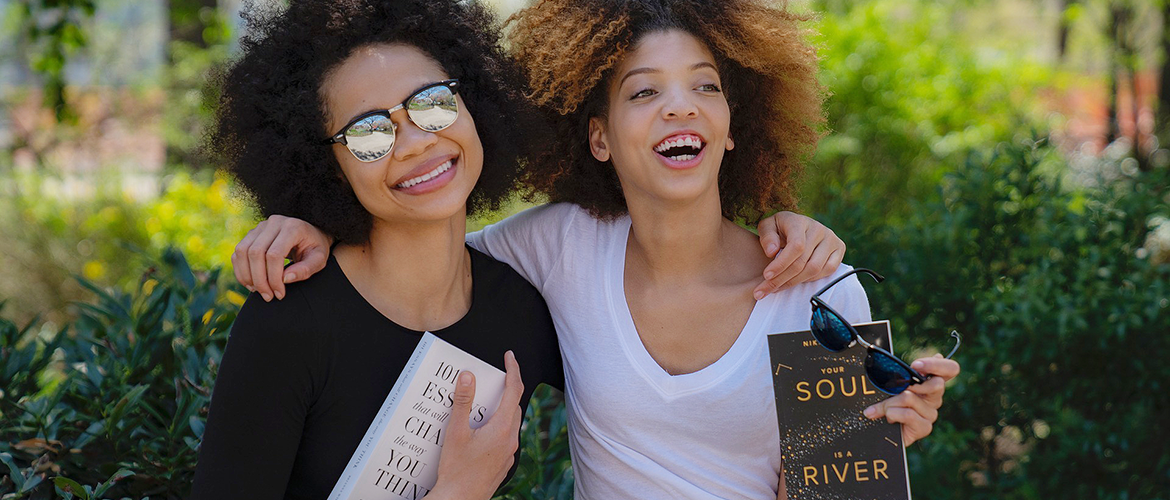 Two teen girls holding books and smiling