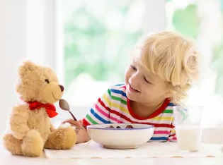 child feeding cereal to teddy bear 