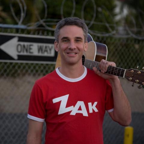 Zak Morgan holding a guitar on his shoulder.