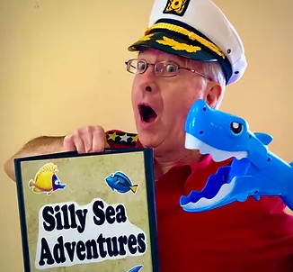 Mark Wood with shark puppet and Silly Sea Adventures sign