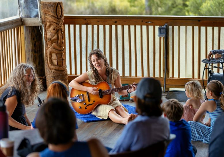 Calliope Pettis playing a guitar in front of an audience of children